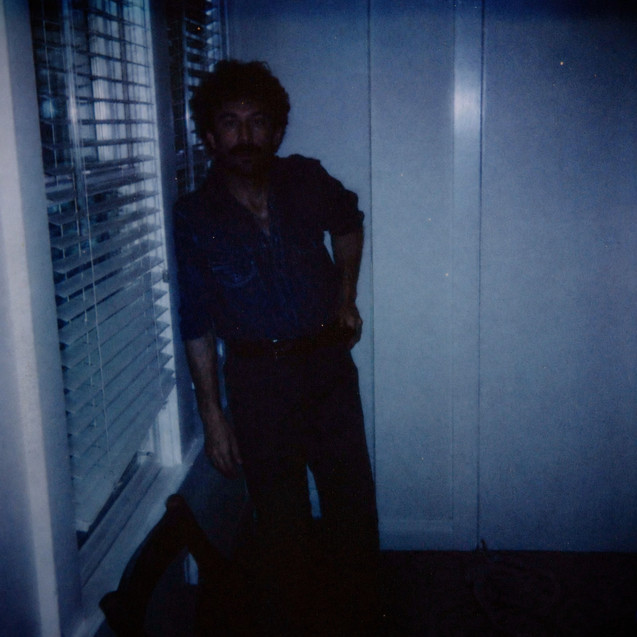 Hogan Ellis standing in a dark blue room beside a window